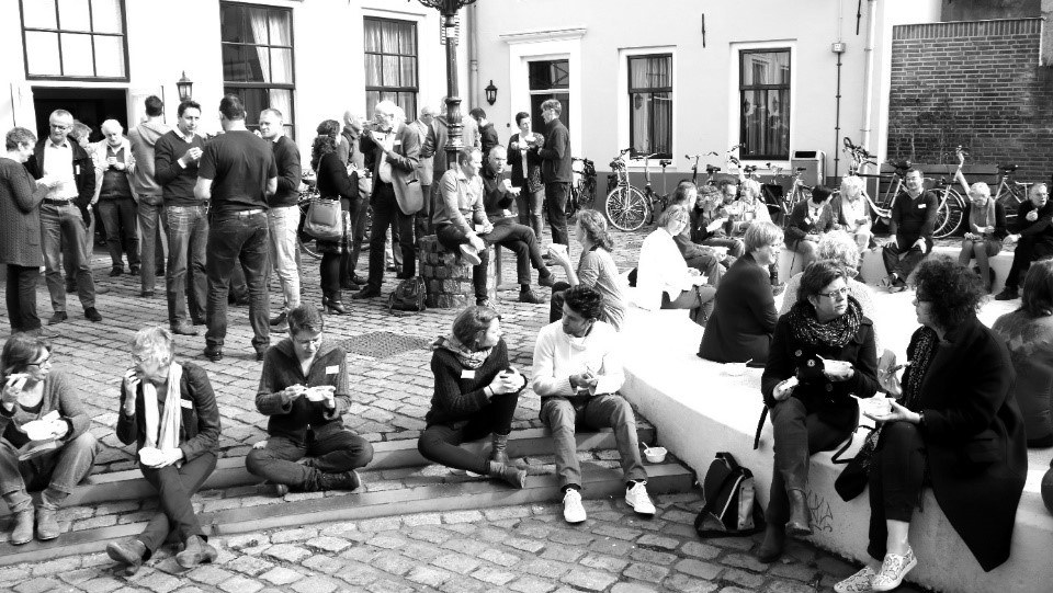 op het pleintje voor het oude weeshuis in Nijmegen is een grote groep zenleraren in opleiding aan het lunchen en praten