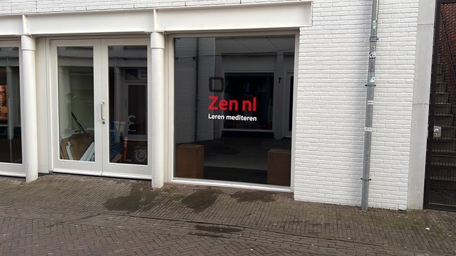 een klinkerstraat in Deventer met een witte gevel, op het raam is het Zen.nl logo te zien